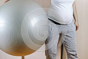 Pregnant woman doing exercises at home on a fitness ball. Copy space - concept of health, sport, safety, quarantine, coronavirus,