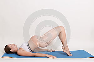 Pregnant woman doing exercises isolated over white background, expectant mother doing gluteal bridge, has gymnastic for pregnant