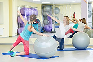 Pregnant woman doing fitness ball exercise with coach