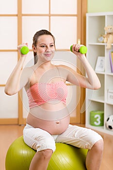 Pregnant woman doing fitness exercises sitting on