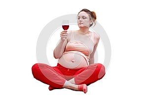 Pregnant woman doing fitness at home and looking at red wine in a gla