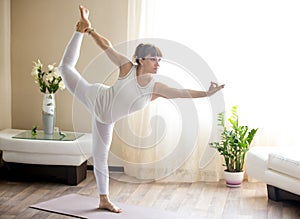 Pregnant woman doing Lord of the Dance yoga pose at home