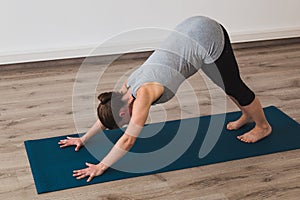 Pregnant woman doing prenatal yoga in downward facing dog posture