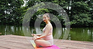 pregnant woman doing prenatal yoga in park near lake, breathing exercises for childbirth