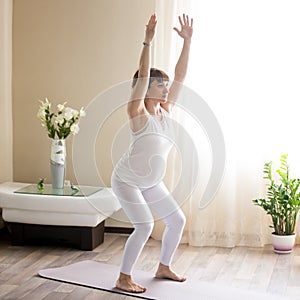 Pregnant woman doing Utkatasana, Chair yoga pose at home