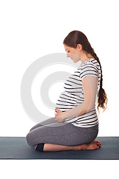 Pregnant woman doing yoga asana Virasana