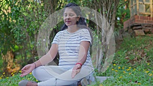 pregnant woman doing yoga breathing exercise in park or garden