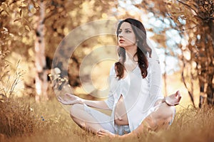 Pregnant woman doing yoga exercise in autumn