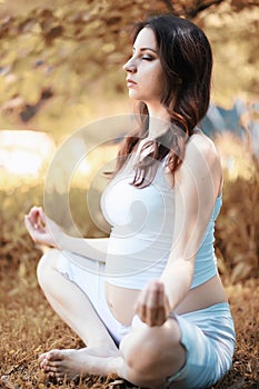 Pregnant woman doing yoga exercise in autumn