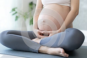 Pregnant Woman Doing Yoga On Exercise Mat. meditating for near-term childbirth of meditating attractive Pregnant female recreation