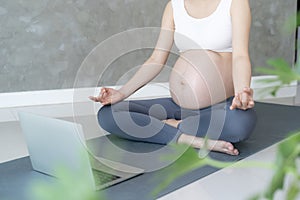 Pregnant Woman Doing Yoga On Exercise Mat. meditating for near-term childbirth of meditating attractive Pregnant female recreation