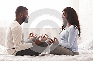 Pregnant woman doing yoga with her husband at home