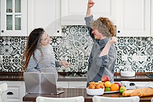 Pregnant woman with dreadlocks and curly husband are dancing in modern kitchen while cooking. Happy pregnancy concept.