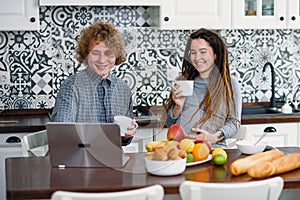 Pregnant woman with dreadlocks and her curly husband in modern kitchen cooking behind. Fresh and healthy food concept.