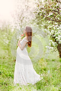 Pregnant woman in a dress in a field of flowers