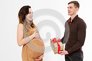 Pregnant woman in dress holds hands on belly and gift box isolated on white background. Pregnancy and maternity concept. Mother