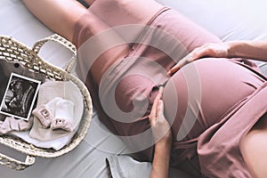 Pregnant woman in dress holds hands on belly. Expectant mother waiting and preparing for baby birth during pregnancy