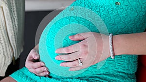 Pregnant woman in dress stoking the belly