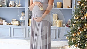 Pregnant woman dressing up a Christmas tree. New Year. background, space for your text