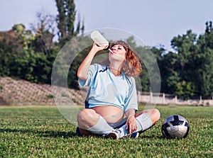 Pregnant woman drink on the soccer field