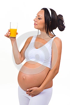 Pregnant woman drinking a glass of fresh orange juice. Isolated on white background