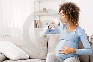 Pregnant woman drinking glass of milk, enjoying healthy drink