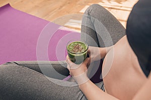 Pregnant woman drinking healthy green smoothie while sitting on