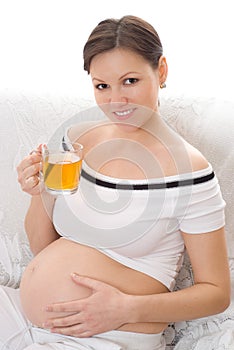 Pregnant woman drinking tea on a white background