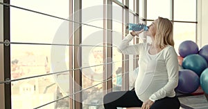 Pregnant woman drinking water in the gym