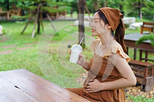 Pregnant woman drinkink milk in garden