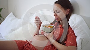 Pregnant woman eat fruit cut in salad in bed, morning breakfast of expecting future mother Spbd