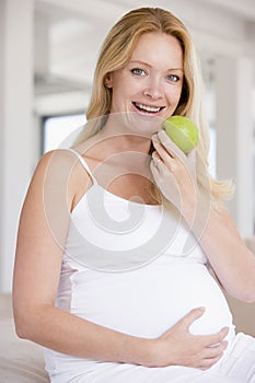 Pregnant woman eating apple and smiling