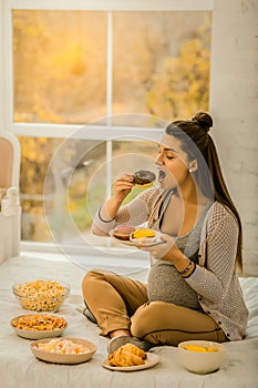 Pregnant woman eating doughnuts and other sweets