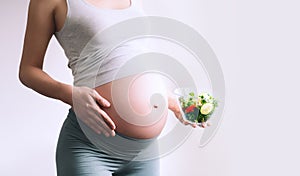 Pregnant woman eating healthy food containing folic acid, B9 vitamin. Close-up pregnant woman`s belly and vegetable salad.