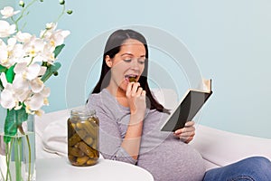 Pregnant woman eating a pickled gherkin.