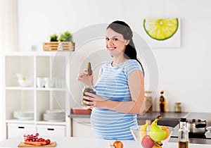 Pregnant woman eating pickles at home kitchen
