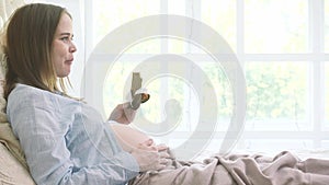 Pregnant woman eating and reading