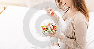 Pregnant woman eating salad with fresh vegetables