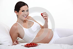 A pregnant woman eating strawberries