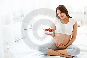 Pregnant Woman Eating Strawberry at home. Healthy Food Concept.