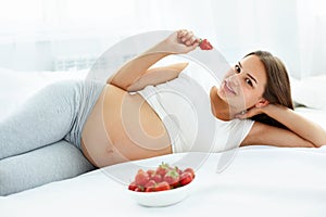 Pregnant Woman Eating Strawberry at home. Healthy Food Concept.