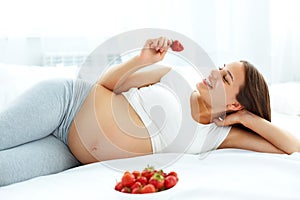 Pregnant Woman Eating Strawberry at home. Healthy Food Concept.