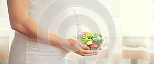 A pregnant woman eats a salad with vegetables. Selective focus