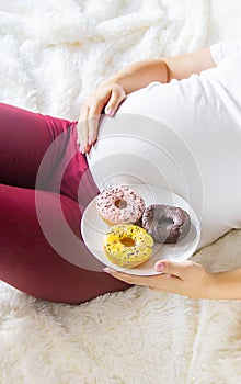 A pregnant woman eats sweet donuts. Selective Focus