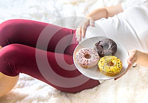 A pregnant woman eats sweet donuts. Selective Focus