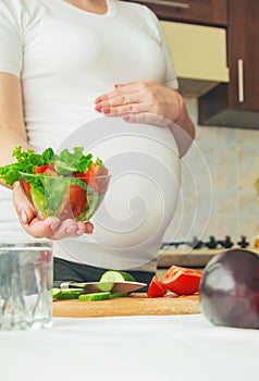 A pregnant woman eats vegetables and fruits. Selective focus