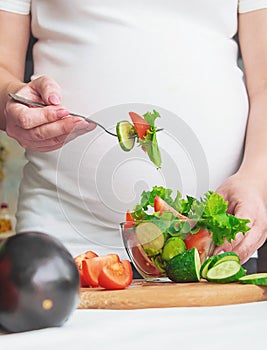 A pregnant woman eats vegetables and fruits. Selective focus.