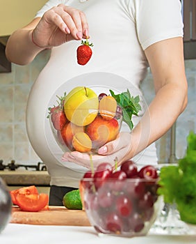 A pregnant woman eats vegetables and fruits. Selective focus.