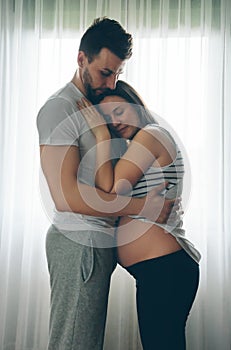 Pregnant woman embraced by her husband