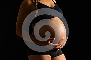 Pregnant Woman Embracing Her Belly on Black Background